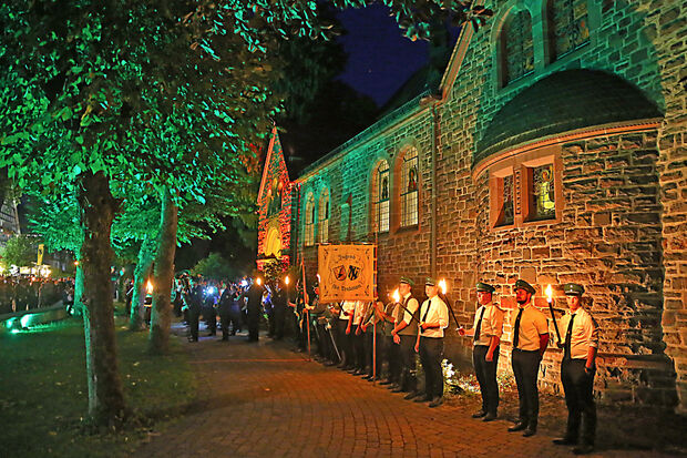 Zum Zapfenstreich an der katholische St.-Jodokus-Kirche wird das historische Steingebäude farbig illuminiert. Hinzu kommt der Schein der Fackeln des Festumzugs. FOTO: ANDREAS DUNKER