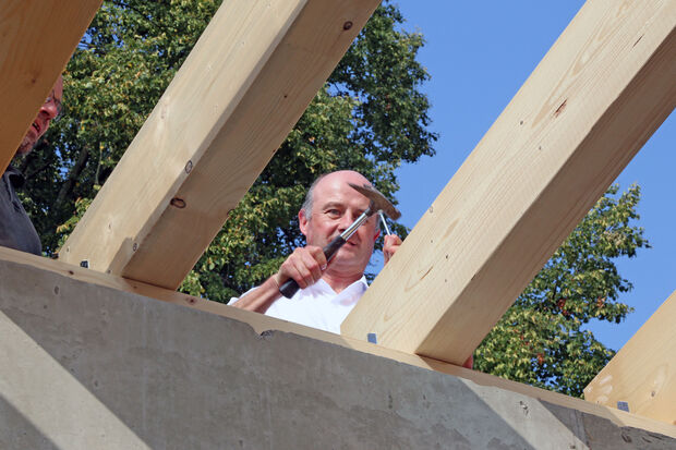 Pfarrer Thomas Metten haut den letzten Nagel ins Dachgebälk. FOTO: ANDREAS DUNKER