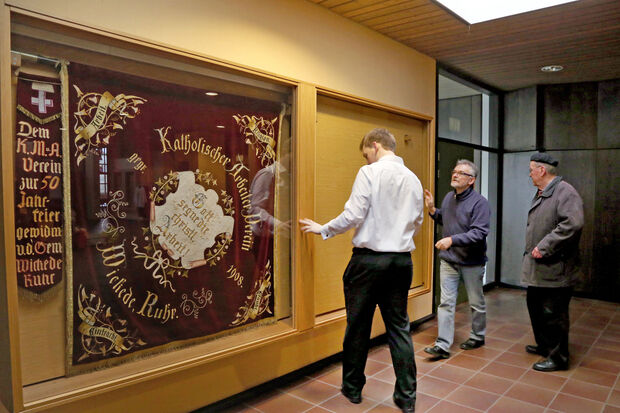 Hans Michalzik (rechts) als letzter Vorsitzender der ehemaligen Katholischen Arbeitnehmer-Bewegung (KAB) holte die historische Fahne des 1908 gegründeten Katholischen Arbeiter-Vereins Wickede (Ruhr) aus der Vitrine im Roncalli-Haus ab. Er will das Banner bis zur Einweihung des neuen Pfarrheimes an der Kirche aufbewahren. Dort soll es möglichst wieder einen Ehrenplatz bekommen und zur Schau gestellt werden. Mit auf dem Bild: Philipp Schulte und Helmut Rubarth FOTO: ANDREAS DUNKER